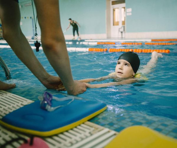 coach-teaching-kid-indoor-swimming-pool-how-swim-dive-swimming-lesson-kids-development (1)